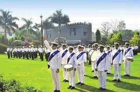 A formal marching band parade with members in white and blue uniforms outdoors.