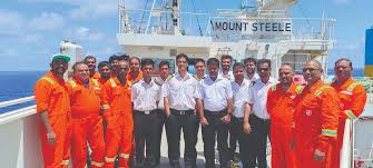 Group of diverse crew members on a cruise ship deck, smiling and posing for photo.