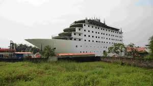 Large cargo ship on dry dock under construction, surrounded by greenery.