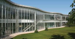 Modern glass office building with sleek architecture and surrounding greenery.